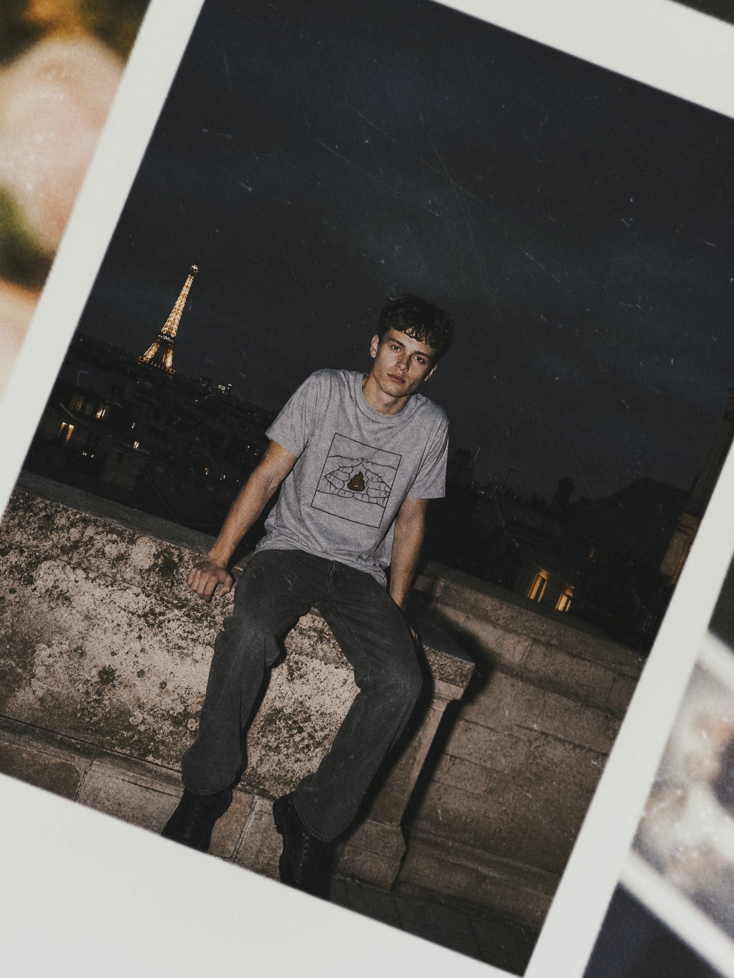 Person sitting on a ledge with the Eiffel Tower in the background at night