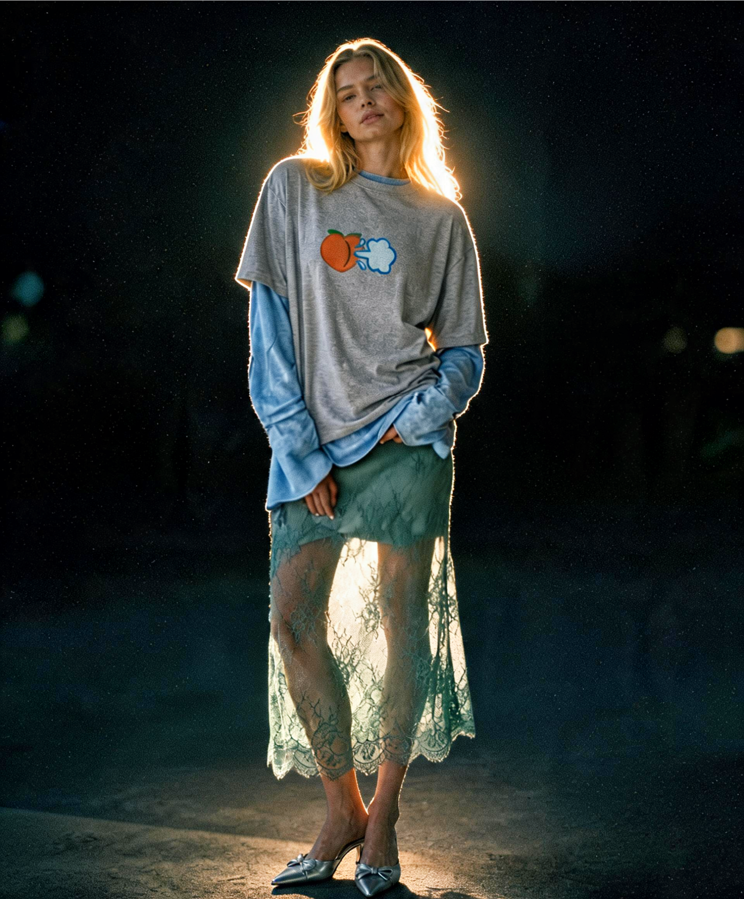 Woman wearing a gray sweatshirt with colorful graphics and a green lace skirt in a dark setting